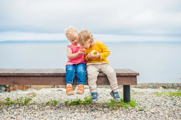 Peuters jongen en meisje zittend op een bankje eet een appel — Stockfoto