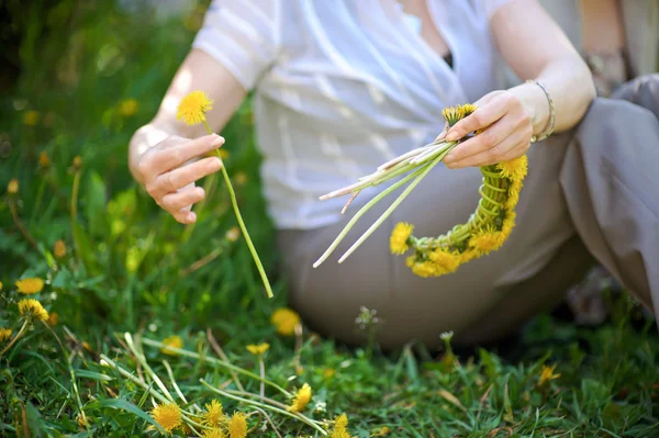 Wreath of yellow dandelions in hands — Stock Photo, Image