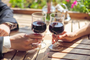 Gelin ve damat tahta masada bir bardak kırmızı şarap içmek