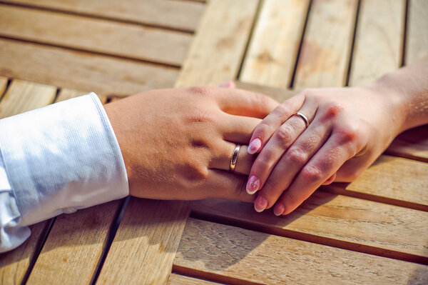 Руки жениха и невесты с обручальными кольцами
