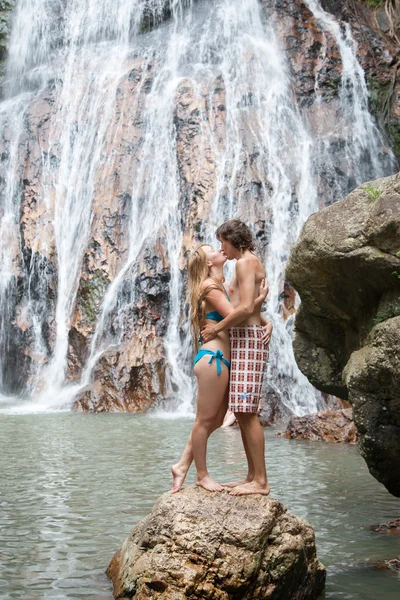 Man en vrouw kussen op de achtergrond van een waterval — Stockfoto