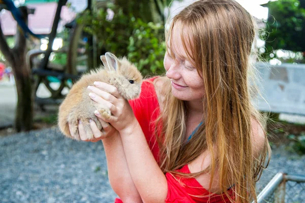 Joven mujer abraza pequeño lindo conejo amigo mascota en sus manos . — Foto de Stock
