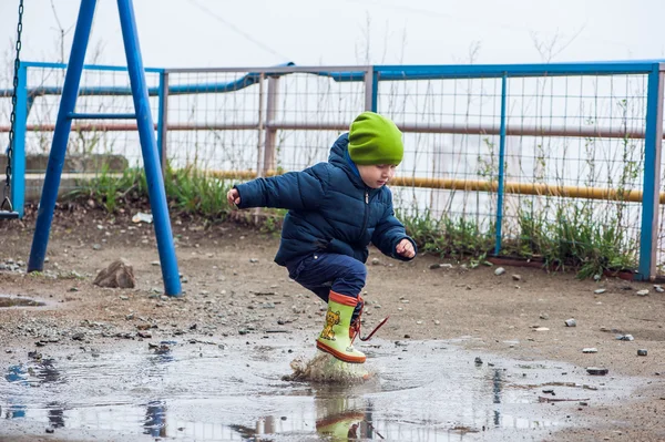 Toddler boy jumping in the puddles — Stock Photo, Image