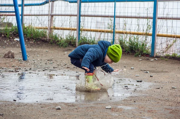 Маленький мальчик прыгает в лужи — стоковое фото