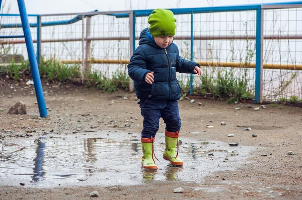 Toddler boy jumping in the puddles — Stock Photo, Image