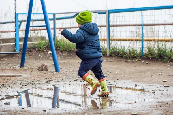 Toddler boy jumping in the puddles — Stock Photo, Image