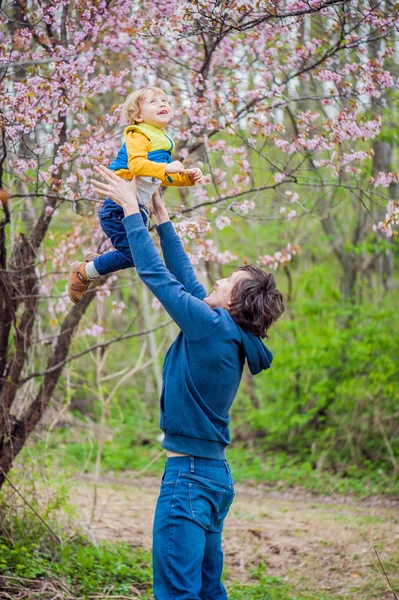 Ο μπαμπάς πετάει επάνω το γιο σε ένα κήπο — Φωτογραφία Αρχείου