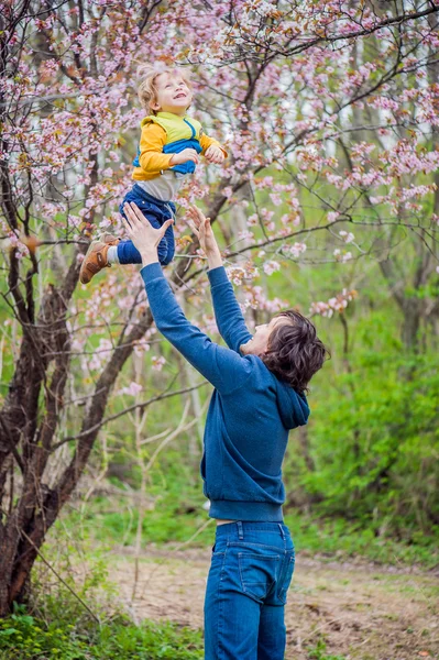 Dad throws up his son in a garden — Stock Photo, Image