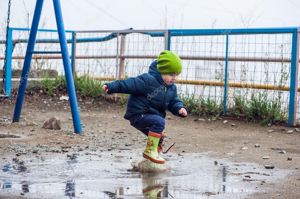 Toddler boy jumping in the puddles