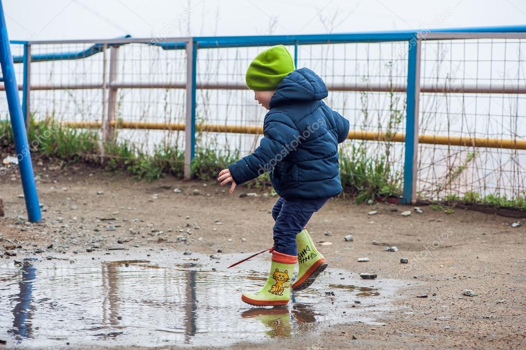 Toddler boy jumping in the puddles