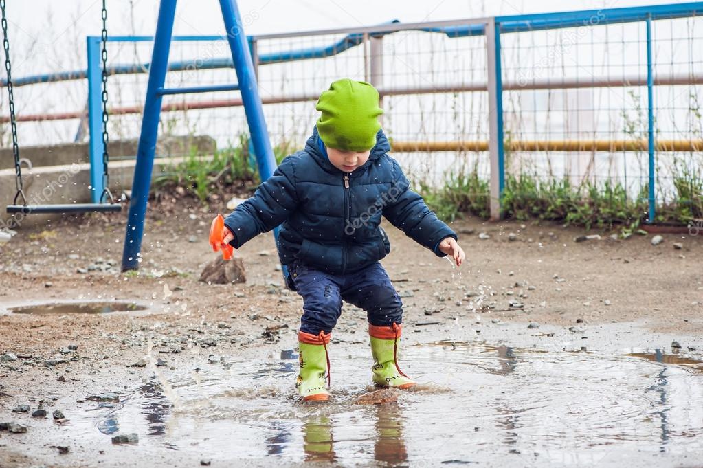 Toddler boy jumping in the puddles