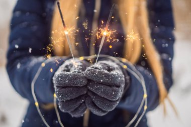 Kıvılcımlar, arka planda kar yağışı yapan kadınların ellerinde. Noel ve Yeni Yıl kavramı