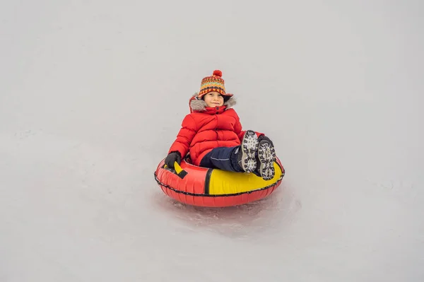 雪のチューブで楽しんでいる子供。男の子はチューブに乗っている。子供のための冬の楽しみ — ストック写真
