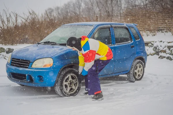 Accidente de invierno en la carretera. Un hombre cambia una rueda durante una nevada. Problemas de invierno — Foto de Stock