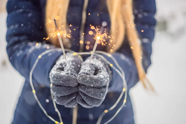 Sparklers em mãos femininas em um contexto da queda de neve. Conceito de Natal e Ano Novo — Fotografia de Stock