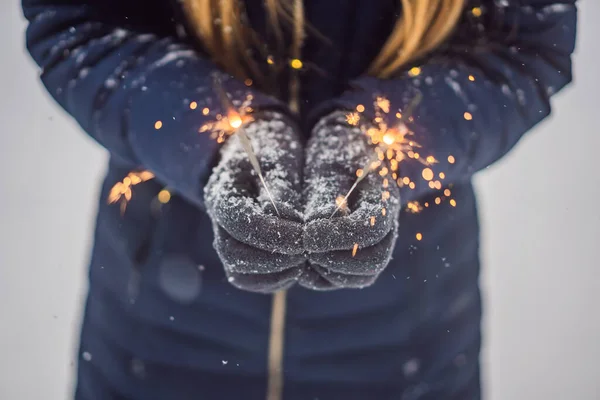 Wunderkerzen in weiblichen Händen vor dem Hintergrund von Schneefall. Weihnachts- und Neujahrskonzept — Stockfoto