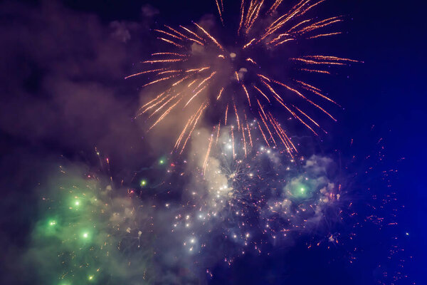 Beautiful colorful holiday fireworks in the evening sky with majestic clouds