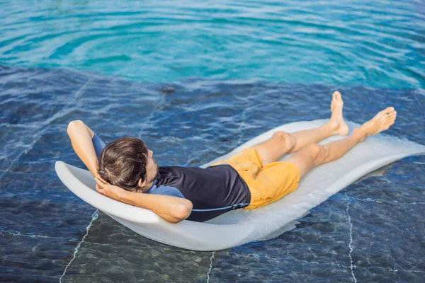 Rilassati in piscina. Giovane e di successo uomo sdraiato su un lettino e abbronzatura in piscina in hotel — Foto Stock