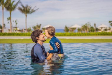Baba ve oğul yüzme havuzunda eğleniyorlar.