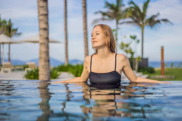 Mulher relaxante na piscina infinita olhando para a vista — Fotografia de Stock