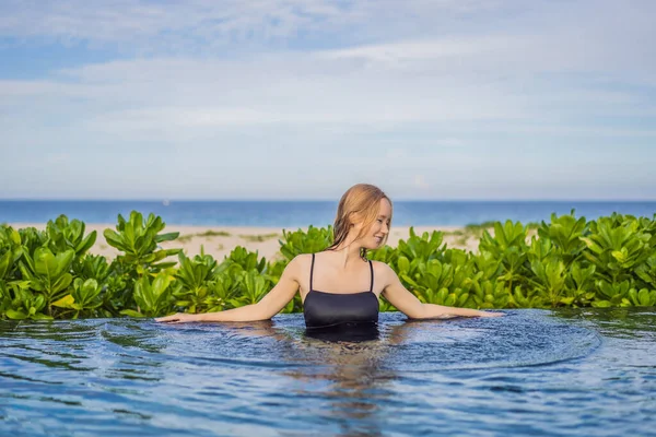Mujer relajante en piscina infinita mirando a la vista —  Fotos de Stock