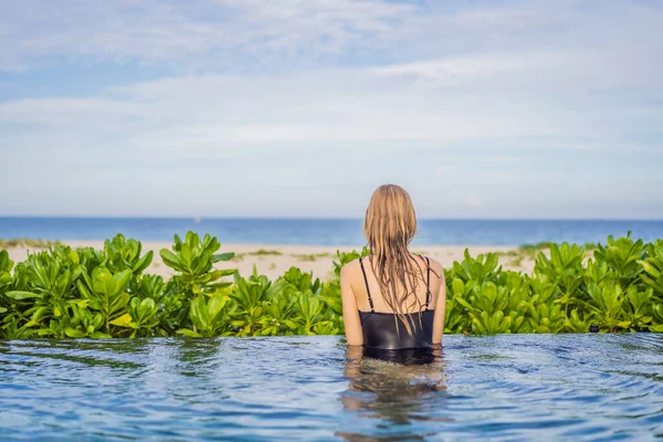 Mujer relajante en piscina infinita mirando a la vista —  Fotos de Stock