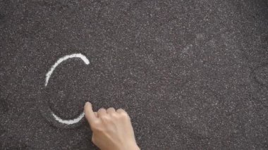 Düz bir yüzeye serpiştirilmiş Chia tohumları ile bir kişi yazar.