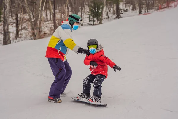 Instruktor snowboardu uczy chłopca jeździć na snowboardzie. Zajęcia dla dzieci w zimie. Zimowy sport dla dzieci. Styl życia — Zdjęcie stockowe