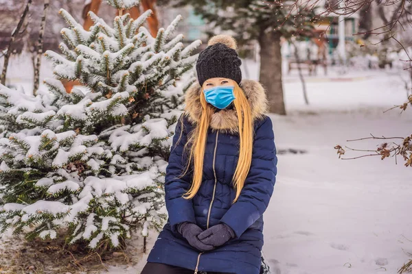 Giovane donna gode di una giornata nevosa invernale in una foresta innevata indossando una maschera medica durante COVID-19 coronavirus — Foto Stock