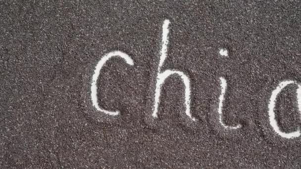 Schriftzug Chia geschrieben in Chia-Samen auf einer ebenen Oberfläche verteilt — Stockvideo