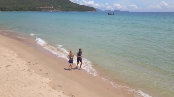 Luftaufnahme eines jungen Mannes und einer jungen Frau beim Joggen an einem schönen Strand. Konzept von gesundem Lebensstil und Sport — Stockvideo