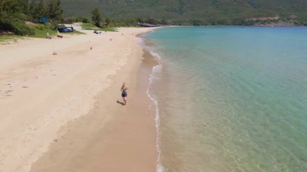 Fotografía aérea en cámara lenta de una joven corriendo en una hermosa playa. Concepto de estilo de vida saludable y deportes — Vídeos de Stock