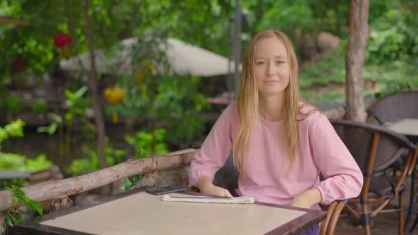 En un café, una mujer joven se niega a tomar una gota de plástico de un solo uso. Ella sostiene un papel con un letrero que NO NECESITO UNA HORA. Concepto de reducción del uso de plástico único — Vídeos de Stock