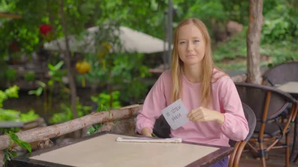 W kawiarni młoda kobieta odmawia wzięcia jednorazowej plastikowej słomki do picia. Trzyma kartkę z napisem "NIE PROWADZAĆ". Koncepcja ograniczenia stosowania pojedynczego tworzywa sztucznego — Wideo stockowe