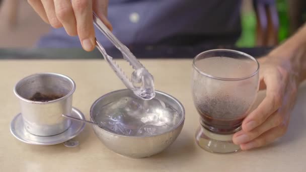 Een jonge man drinkt Vietnamese koffie in een café — Stockvideo