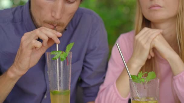 Em um café jovem casal ter uma conversa. Eles bebem suas bebidas usando palhas de aço reusabla. Conceito de reduzir o uso de plástico único — Vídeo de Stock