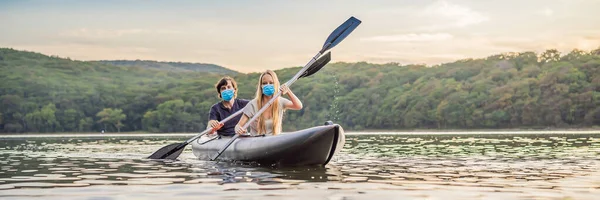 BANNER, LONG FORMAT Férfi és nő úszik kajak visel orvosi maszk miatt a COVID-19 koronavírus a tengerben a háttérben a sziget. Kayaking koncepció.Kayaking koncepció a család apa anya — Stock Fotó