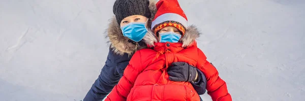 Máma syn jezdit na nafukovací zimní sáně hadice nosit lékařské masky kvůli COVID-19 coronavirus. Zimní zábava pro celou rodinu BANNER, DLOUHÝ FORMÁT — Stock fotografie
