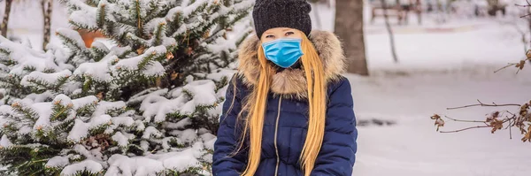Giovane donna gode di una giornata nevosa invernale in una foresta innevata indossando una maschera medica durante COVID-19 coronavirus BANNER, FORMATO LUNGO — Foto Stock