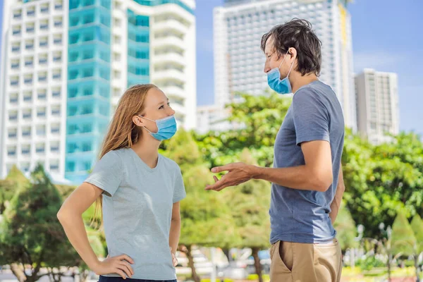 Egy férfi és egy nő kommunikál az utcán helytelenül viselt arcmaszkokkal. Orvosi maszkok helytelen viselése — Stock Fotó
