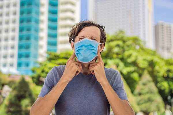 Onjuist dragen van masker concept. Een man krabt onder het masker en raakt het masker aan. — Stockfoto