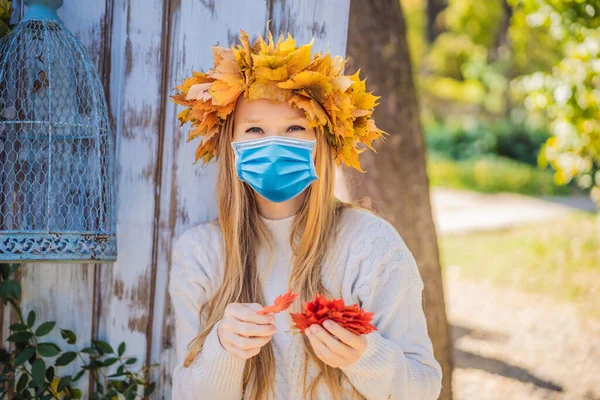 야외에서의 생활 방식은 코로나 바이러스 (COVID-19 코로나 바이러스 ) 도중 의학용 마스크를 착용하고 가을 잎을 입고 있는 매력적 인 금발의 젊은 여성의 모습과 밀접 한 관련이 있다. 세련 된 뜨개질 도르래를 착용하고 있다. 브 랏 — 스톡 사진