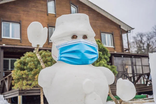 Zimní říše divů s legračním usměvavým sněhulákem v lékařské masce během COVID-19 koronaviru ve zasněženém parku. Bílá kopie prostor pro pozdrav nebo slavnostní text — Stock fotografie