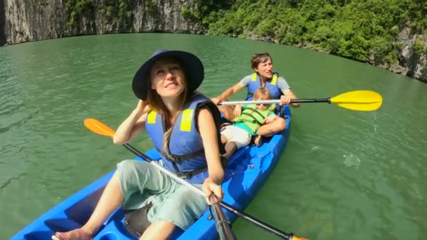 Fotografía en cámara lenta de una feliz familia de turistas navegando en kayak entre acantilados de piedra caliza en un parque nacional de Halong Bay, Vietnam. Viajar al concepto de Vietnam — Vídeo de stock