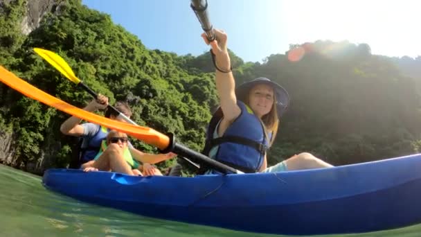 Fotografía en cámara lenta de una feliz familia de turistas navegando en kayak entre acantilados de piedra caliza en un parque nacional de Halong Bay, Vietnam. Viajar al concepto de Vietnam — Vídeo de stock