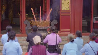 Budist tapınağında dua eden bir grup yaşlı Asyalı kadın.