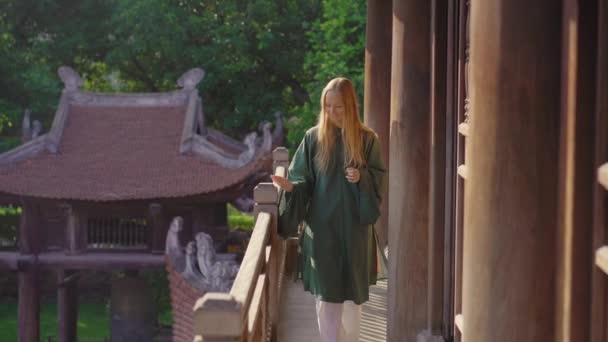 Jeune voyageuse visite le temple de la Littérature à Hanoi. Elle porte une robe vietnamienne traditionnelle pour les étudiants. Voyage au Vietnam concept — Video