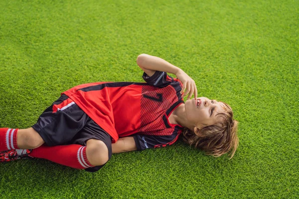 Little cute kid boy in red football uniform and his trainer or father playing soccer, football on field, outdoors. Active child making sports with kids or father, Smiling happy boy having fun in — Stock Photo, Image