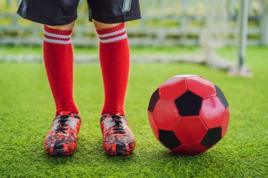 Kırmızı futbol forması giyen, futbol oynayan, sahada, dışarıda futbol oynayan tatlı bir çocuk. Aktif çocuk çocuklarla ya da babayla spor yapıyor, gülen mutlu çocuk yazın eğleniyor.