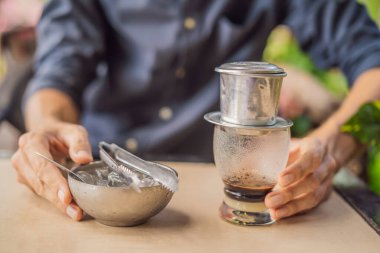 Beyaz adam ve geleneksel damlalar Vietnam kahvesini bir filtreden demledi.